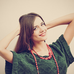 Attractive smiling trendy woman posing against white wall, image with warm vintage toning and...
