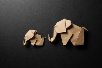 Brown paper origami elephant isolated on black paper background