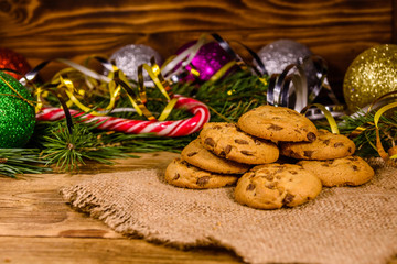 Pile of the chocolate chip cookies on sackcloth in front of christmas decorations