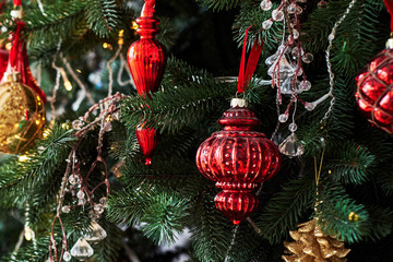 Christmas tree decorated with red and gold baulbes, garland light, copy space. Winter holidays or New year concept, close up