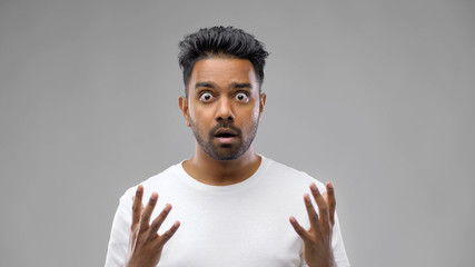 emotion, expression and people concept - shocked indian man over grey background