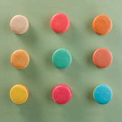 Creative layout of colorful macaroons on a green background. Flat lay. Nutrition concept.