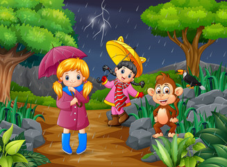 Obraz na płótnie Canvas Two girl carrying umbrella goes under a rain with monkey