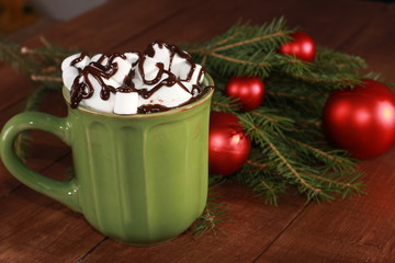 Cocoa and Christmas baubles on vintage wooden table. Christmas concept. Marshmallow, fir tree branches, green cup, chocolate, closeup