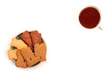 An overhead photo of an assortment of traditional Christmas Spekulatius cookies, shot from the top on a white background with hot chocolate and a place for text