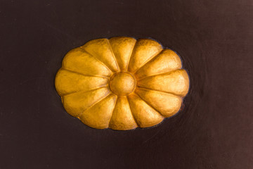 Golden ornament in the form of a flower with patina