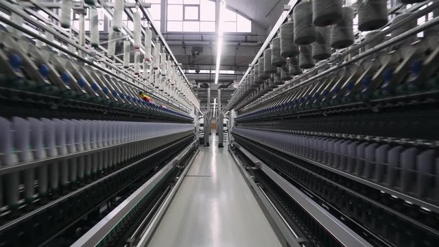 Spinning factory, production of fabrics, thread of silk, linen, and synthetics, view of tunnels of production line on light industry.