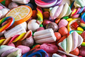 different colors of candy, lollipops, chewing gum, marshmallow and other sweets. The background is sweet