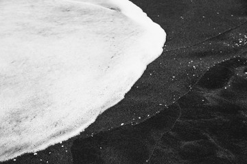 foam from the waves and black sand