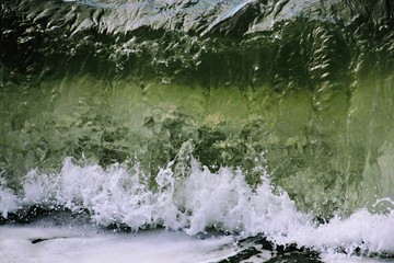 the green wave breaks on the shore and foams