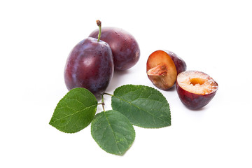 Group of whole and half of ripe plums with leaf isolated on a white background..