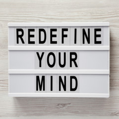 'Redefine your mind' words on modern board over white wooden background, top view. Overhead, flat lay, from above.