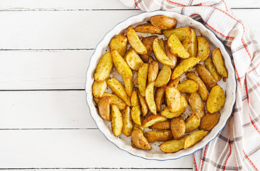 Ruddy Baked potato wedges with garlic on a white background. Flat lay. Top view.