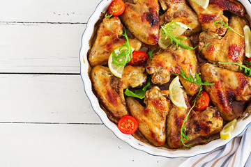 Baked chicken wings in plate on wooden table. Top view.