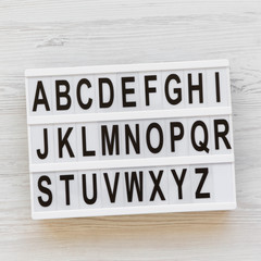 Letters from A to Z. English alphabet on modern board over white wooden surface, overhead view. Back to school concept. From above, flat lay, top view.