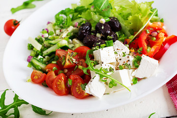 Healthy food. Greek salad of fresh cucumber, tomato, sweet pepper, lettuce, onion, feta cheese and black olives with olive oil. Buddha bowl.