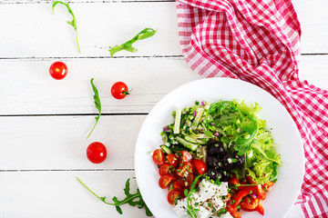 Healthy food. Greek salad of fresh cucumber, tomato, sweet pepper, lettuce, onion, feta cheese and black olives with olive oil. Buddha bowl. Top view