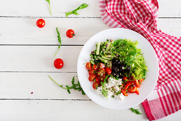Healthy food. Greek salad of fresh cucumber, tomato, sweet pepper, lettuce, onion, feta cheese and black olives with olive oil. Buddha bowl. Top view