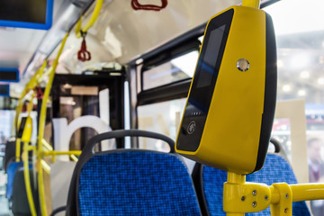 modern and comfortable City vehicle bus salon with empty passenger seats. Focus on yellow validator