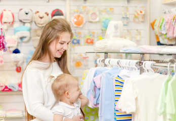 woman with a small child choose baby clothes in the store