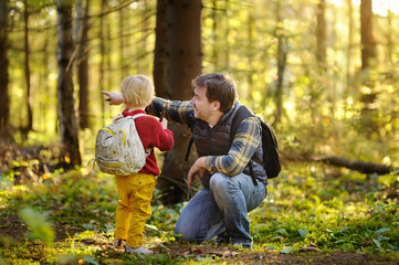 Fototapeta premium Father and his little son walking during the hiking activities in forest at sunset.