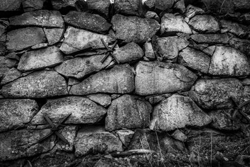 Closeup of black and white rock stone wall outdoors. Old vintage grunge texture structure.