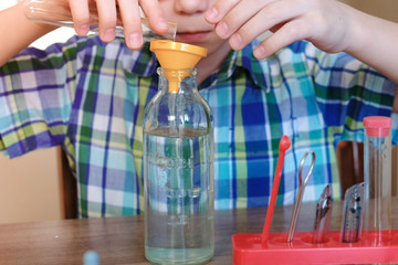 Experiments on chemistry at home. Close-up of the boy's hands poured water from the tube into the...