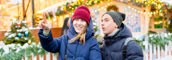 young happy smiling couple talking and point finger while walking in the europe city on a winter smowy day f
