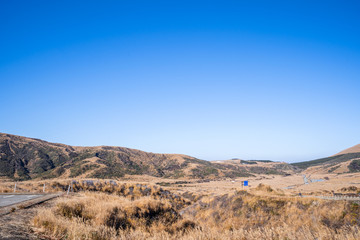 Aso mountain and dry brown grassland with miscanthusm in autumn, blue sky.