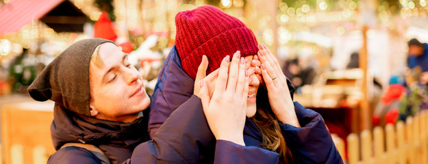 young man closes eyes to his female and makes a surprise on a winter holidays outdoors f