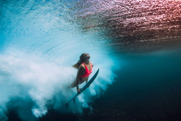 Sporty surfer woman dive underwater with under barrel wave.