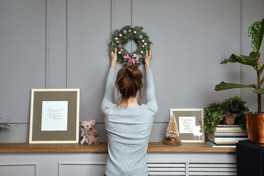  Girl hanging a wreath on a gray wall, sun light