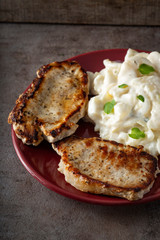 Fried pork chops with potatoes salad on a red plate