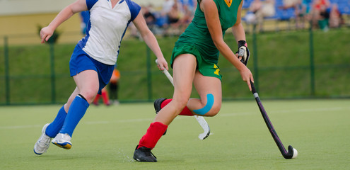 Obraz premium Two women battle for control of ball during field hockey game