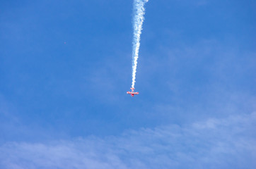 red airplane doing acrobatics in blue sky