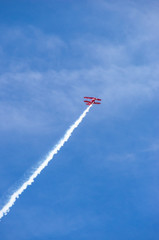 red airplane doing acrobatics in blue sky