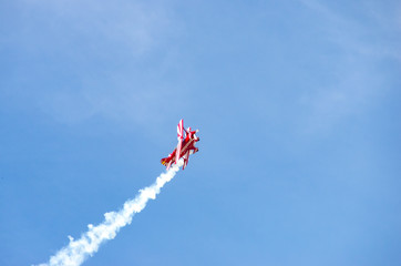 red airplane doing acrobatics in blue sky