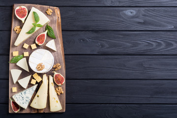 Cheeseboard with cheese brie , parmesan , camembert and dorblu . Food on wooden board