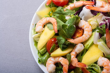 Mix of salad with shrimps , avocado and cherry tomatoes . Healthy food background