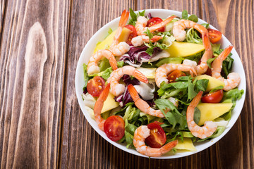 Mix of salad with shrimps , avocado and cherry tomatoes . Healthy food background