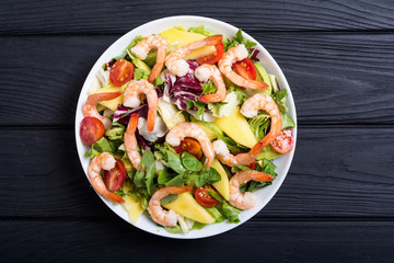 Mix of salad with shrimps , avocado and cherry tomatoes . Healthy food background