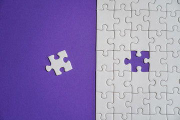 Fragment of a folded white jigsaw puzzle and a pile of uncombed puzzle elements against the...