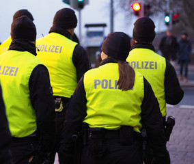 Bremen, Germany - Group of police officers in black uniforms and hi-viz vests patrolling the christmas market