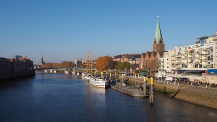 Fototapeta na wymiar Bremen, Germany - View of the river Weser and the historic Schlachte waterfront with the spire of St. Martini church