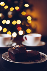 Christmas chocolate muffin on bokeh background and cups with tea, in gold and brown tones