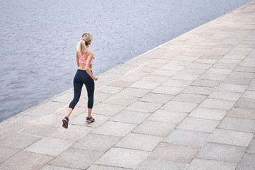 Serious about staying in shape. Top view of young woman in sports clothing jogging while exercising outdoors