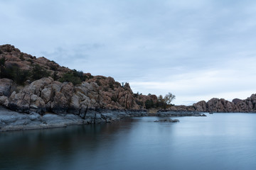 Fototapeta na wymiar long exposure of The Dells rock formations at Watson Lake in Prescott, Arizona on a gray sky morning with dramatic clouds