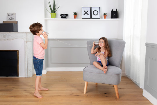 Boy and girl playing with tin can telephone