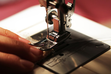 The woman works on the sewing machine. Clothes manufacture.