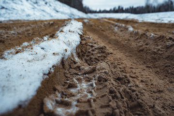 Car Tire Marks on an Empty Field Covered With Snow, Wood in the Background